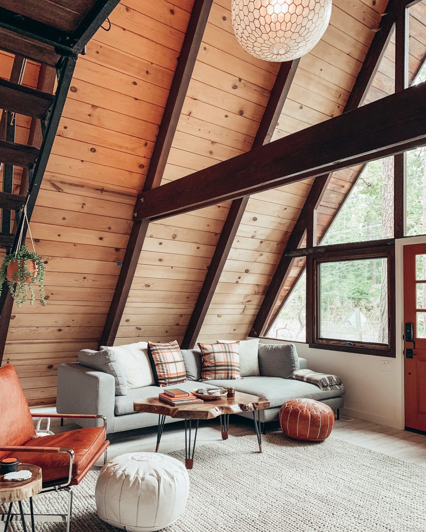 What to Stream on Netflix During Covid 19 by popular San Francisco lifestyle blog, Just Add Glam: image of a A Frame cabin interior with a tan braided rug, leather arm chair, honeycomb pendant light, grey sectional couch, and leather poufs. 